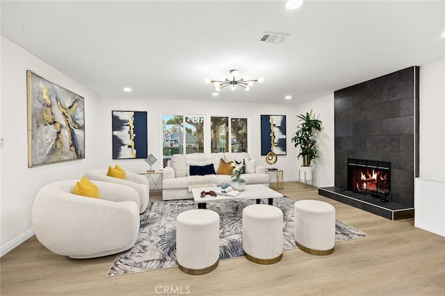 living area featuring light wood-style floors, visible vents, a fireplace, and baseboards