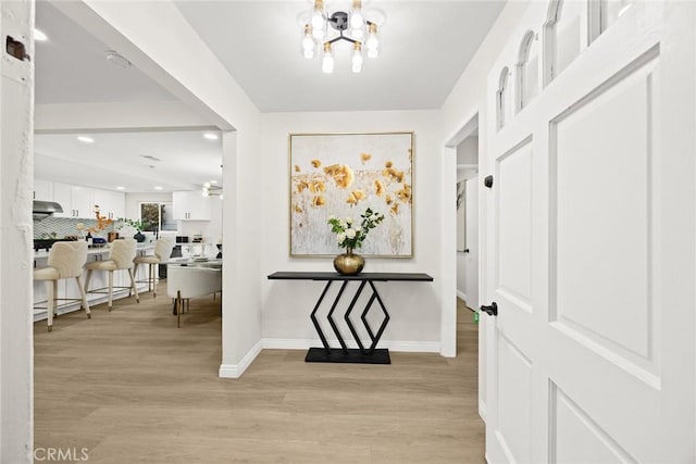 interior space featuring light wood-style flooring, baseboards, a notable chandelier, and recessed lighting