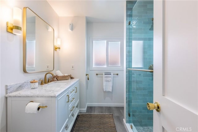 bathroom with baseboards, a shower stall, vanity, and wood finished floors