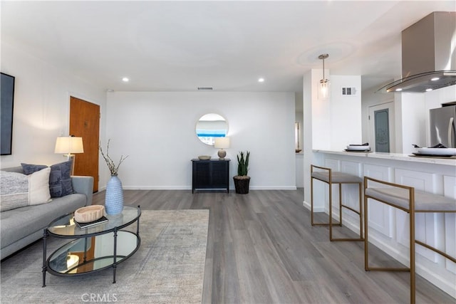 living room featuring recessed lighting, visible vents, baseboards, and wood finished floors