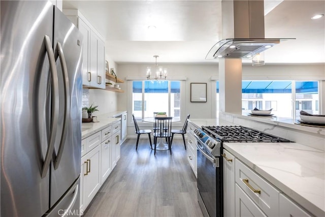 kitchen featuring a chandelier, extractor fan, stainless steel appliances, wood finished floors, and white cabinetry