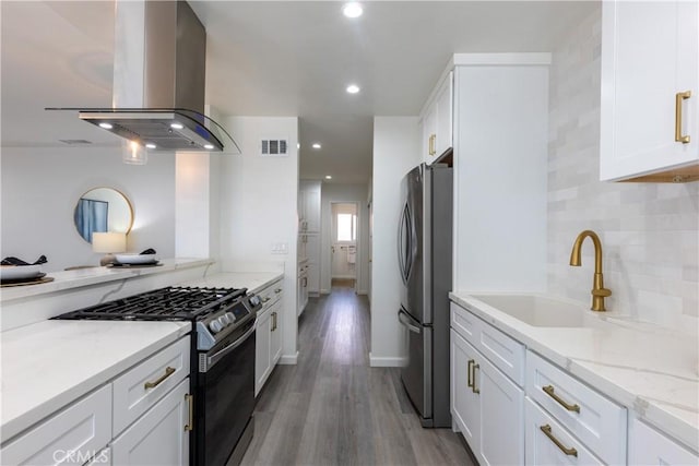 kitchen featuring visible vents, island exhaust hood, stainless steel appliances, white cabinetry, and a sink