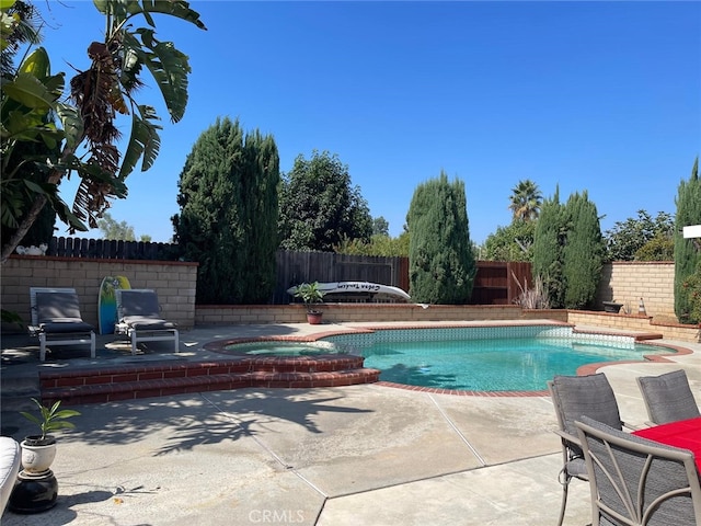 view of pool featuring a pool with connected hot tub, a fenced backyard, and a patio