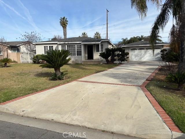 view of front facade with stucco siding, an attached garage, fence, driveway, and a front lawn