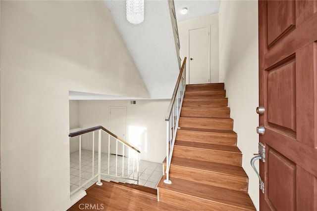 staircase with a textured ceiling and tile patterned floors