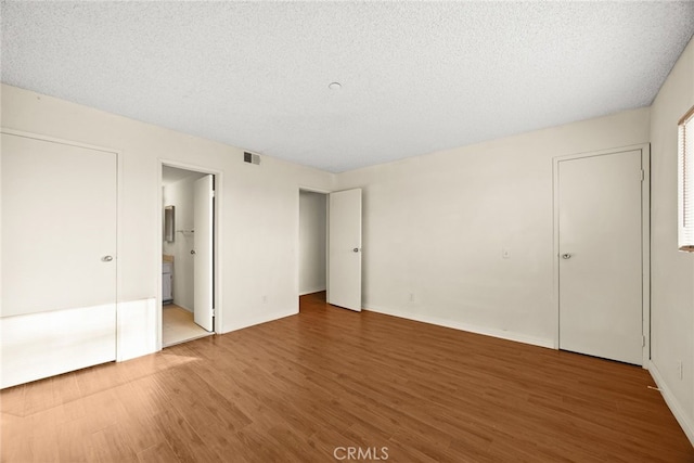 11331 Elliott Ave Unit 21, El Monte, CA 91732 - unfurnished bedroom with wood finished floors, connected bathroom, baseboards, and a textured ceiling