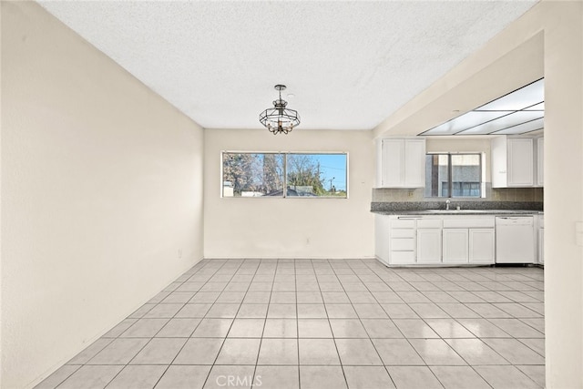 kitchen featuring light tile patterned floors, decorative backsplash, dishwasher, dark countertops, and white cabinetry