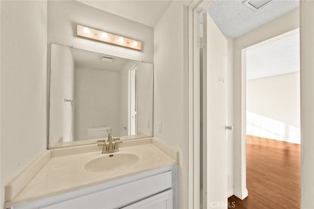 bathroom with a textured ceiling, wood finished floors, and vanity