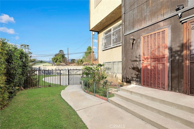 property entrance featuring fence, a lawn, and stucco siding