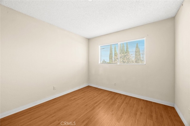 unfurnished room featuring light wood-style flooring, baseboards, and a textured ceiling