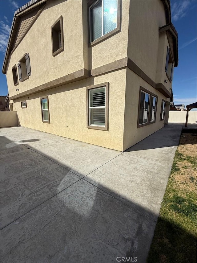 view of home's exterior featuring fence, a patio, and stucco siding