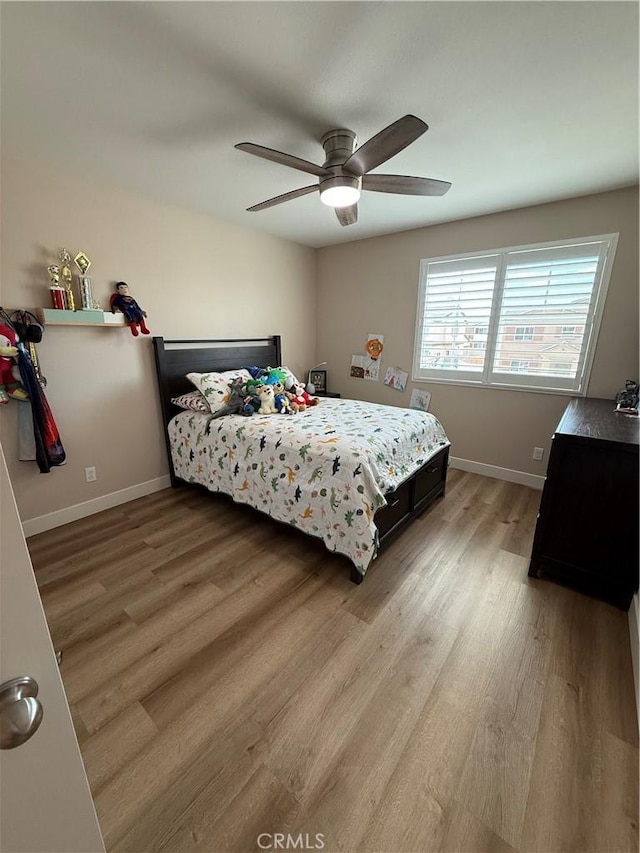 bedroom featuring a ceiling fan, light wood-style flooring, and baseboards