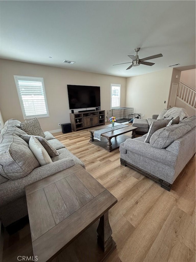 living room with light wood-type flooring, visible vents, and ceiling fan