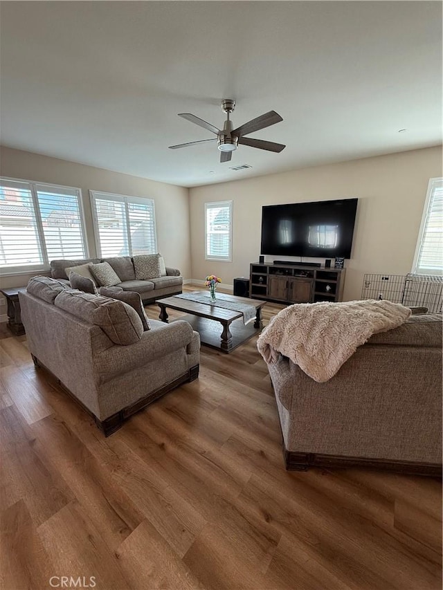 living area with a ceiling fan, visible vents, and wood finished floors