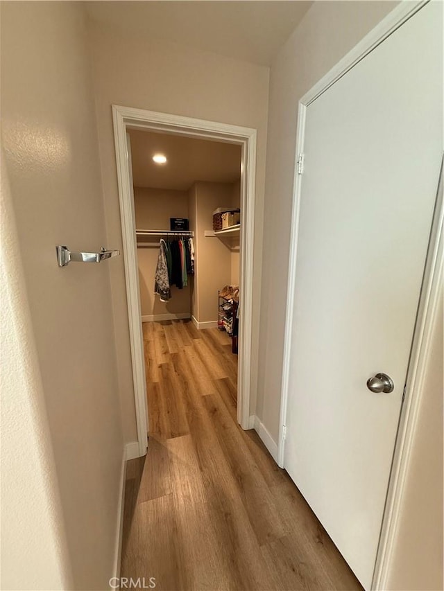 corridor with baseboards and light wood finished floors