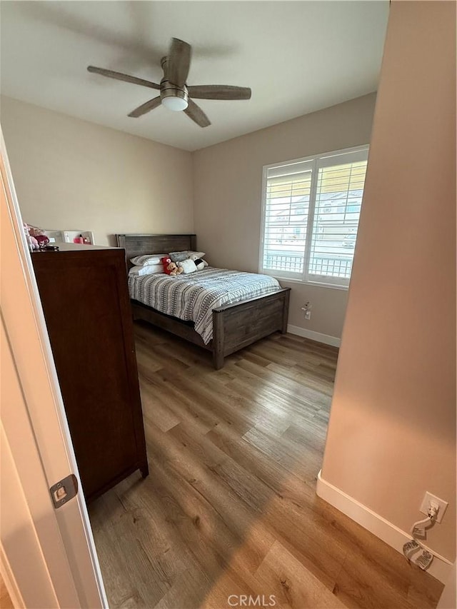 bedroom with wood finished floors, a ceiling fan, and baseboards