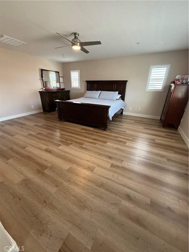 unfurnished bedroom featuring light wood-style floors, multiple windows, and baseboards