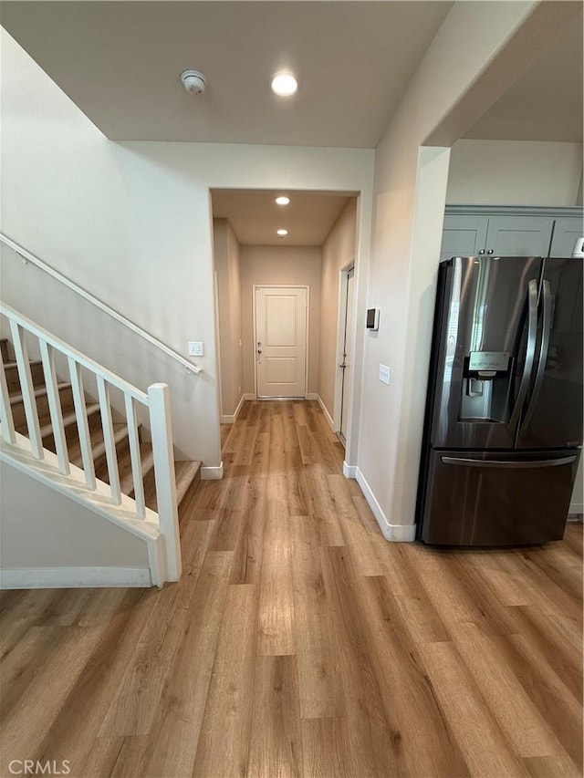 corridor with stairs, light wood finished floors, recessed lighting, and baseboards