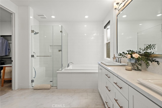 bathroom featuring double vanity, a stall shower, a garden tub, a sink, and recessed lighting