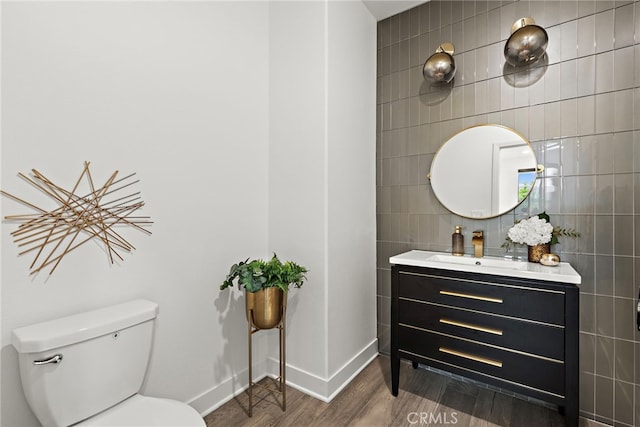 bathroom featuring toilet, vanity, wood finished floors, and tile walls