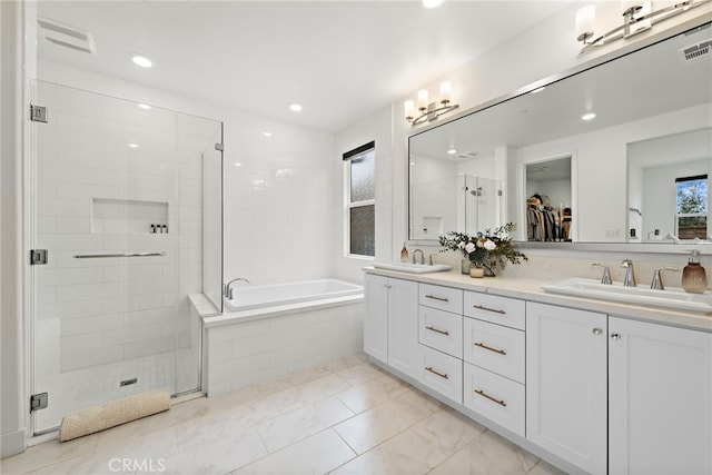 full bathroom with double vanity, a stall shower, marble finish floor, a garden tub, and a sink