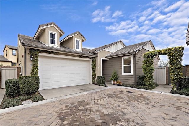 view of front facade featuring a garage, decorative driveway, fence, and stucco siding