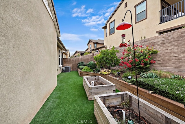 view of yard featuring central air condition unit, fence, and a vegetable garden