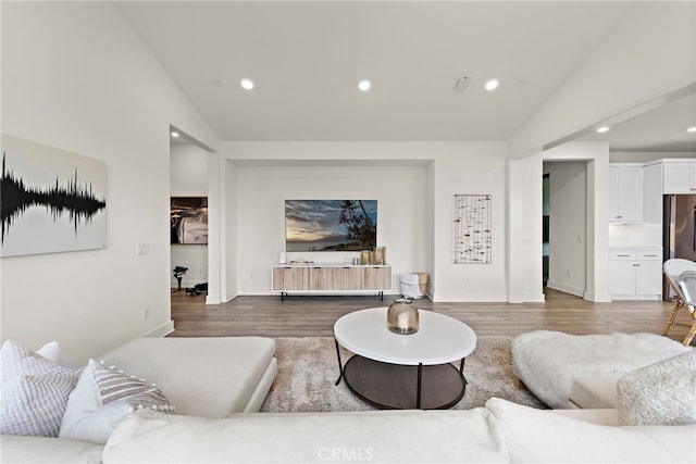 living area featuring recessed lighting, vaulted ceiling, baseboards, and wood finished floors