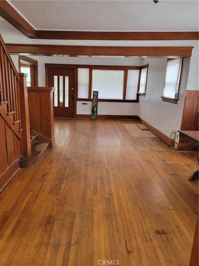 unfurnished living room with hardwood / wood-style floors, stairway, and baseboards