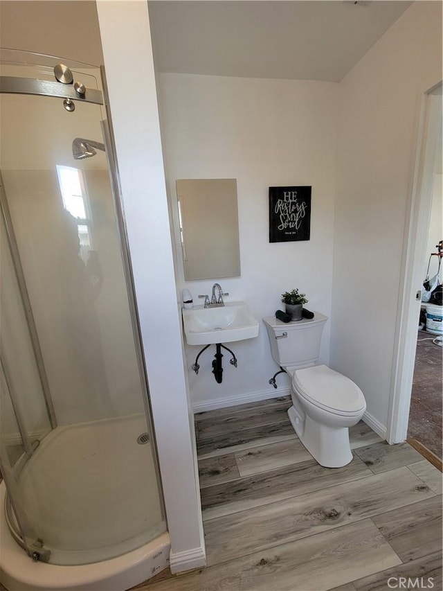 bathroom with a sink, a shower stall, toilet, and wood finished floors