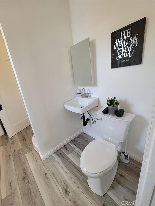 bathroom with a sink, toilet, baseboards, and wood finished floors