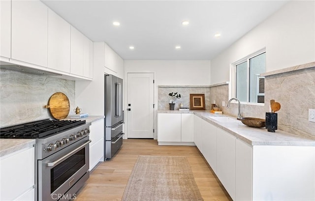 kitchen featuring light countertops, a sink, high quality appliances, and white cabinets