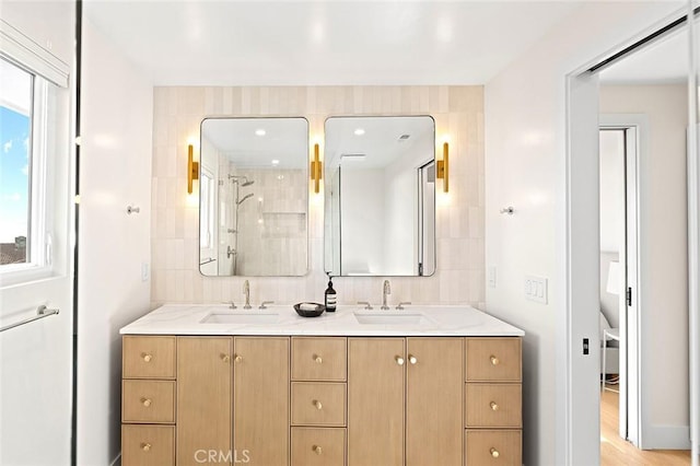 bathroom featuring a tile shower, double vanity, and a sink