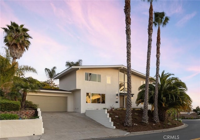 mid-century inspired home with an attached garage, concrete driveway, and stucco siding