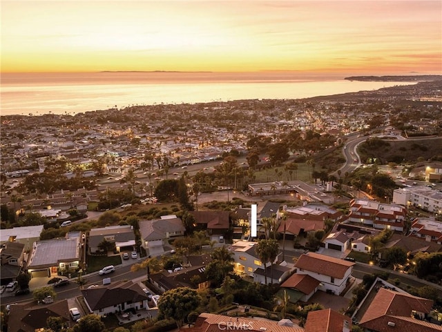 aerial view at dusk with a water view and a residential view