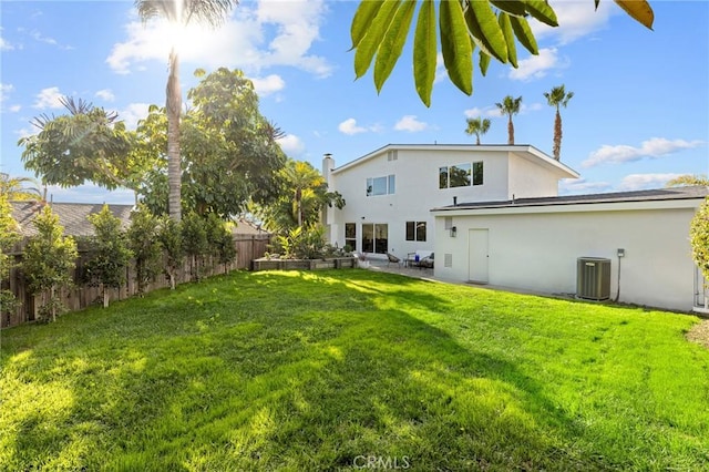 rear view of house with central air condition unit, a fenced backyard, a lawn, and stucco siding