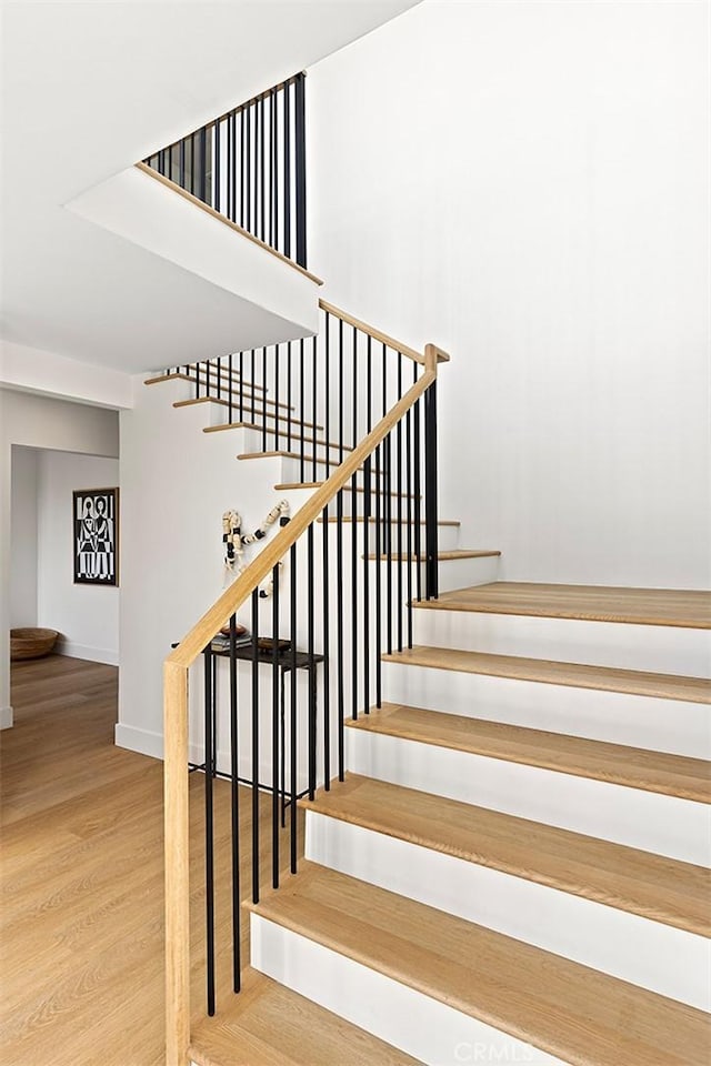 staircase with baseboards and wood finished floors