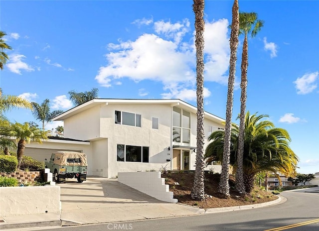 view of front facade with concrete driveway, an attached garage, and stucco siding