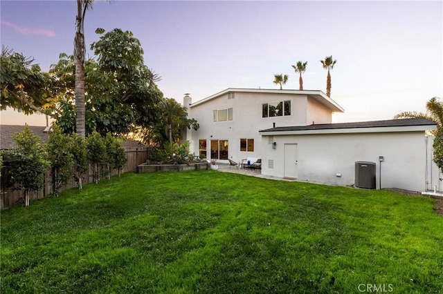 back of house with stucco siding, a fenced backyard, a yard, and central air condition unit