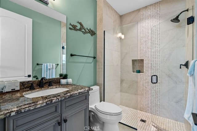 bathroom featuring toilet, a shower stall, and vanity