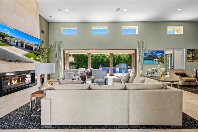 living room featuring a wealth of natural light, a tile fireplace, a high ceiling, and recessed lighting