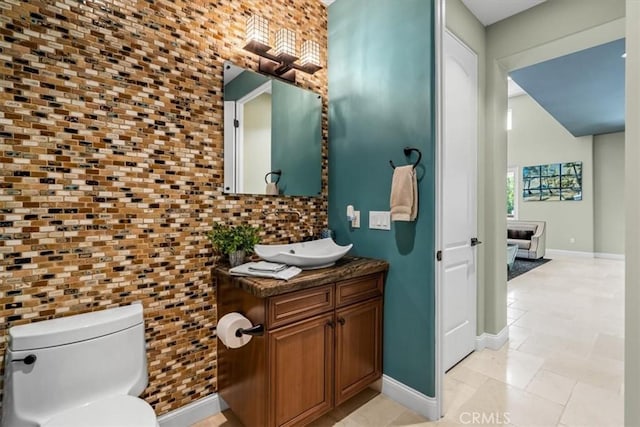 half bath with baseboards, vanity, and toilet