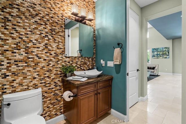 bathroom with toilet, vanity, and baseboards