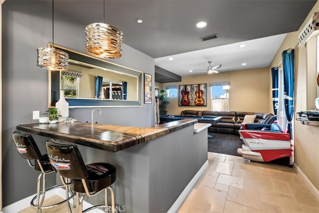 bar with indoor wet bar, recessed lighting, visible vents, a ceiling fan, and baseboards