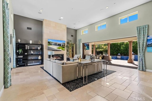 living area featuring recessed lighting, a fireplace, a towering ceiling, baseboards, and visible vents