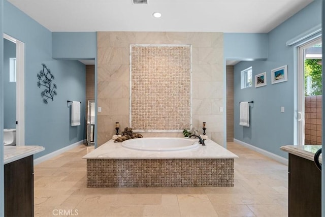 bathroom with visible vents, baseboards, toilet, a garden tub, and tile walls