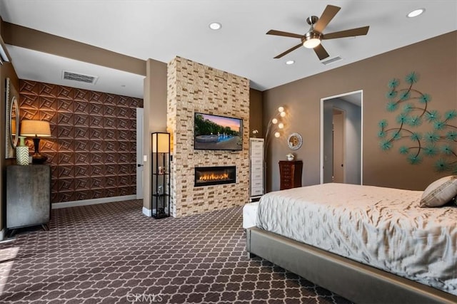 bedroom with a large fireplace, dark carpet, visible vents, and recessed lighting