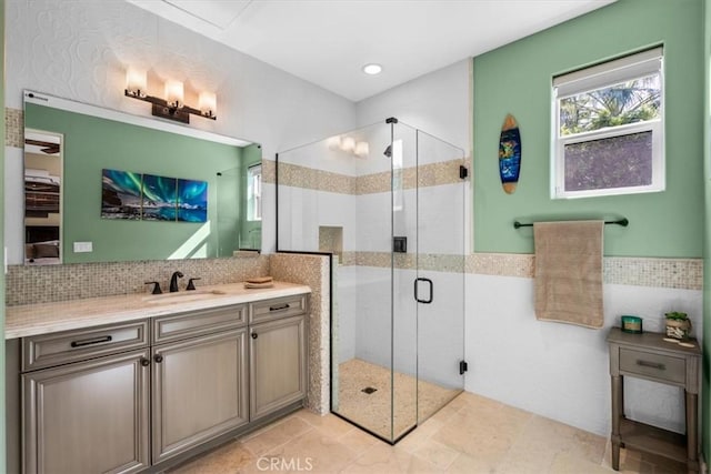 bathroom with a stall shower, a wainscoted wall, tile walls, and vanity