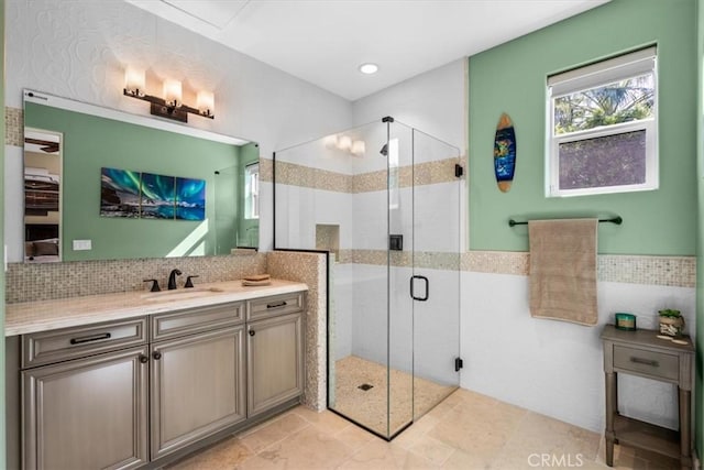 bathroom with tile walls, a shower stall, vanity, and decorative backsplash