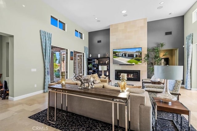 living area featuring a large fireplace, a towering ceiling, recessed lighting, and visible vents